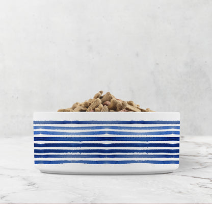 White bowl with blue stripes filled with pet food on a light gray background
