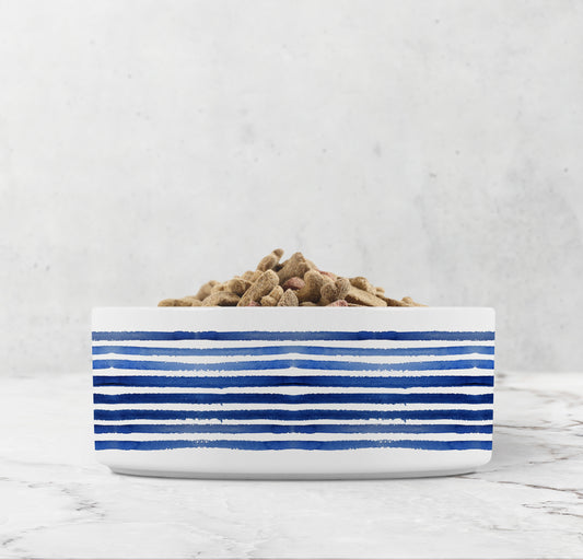 White bowl with blue stripes filled with pet food on a light gray background