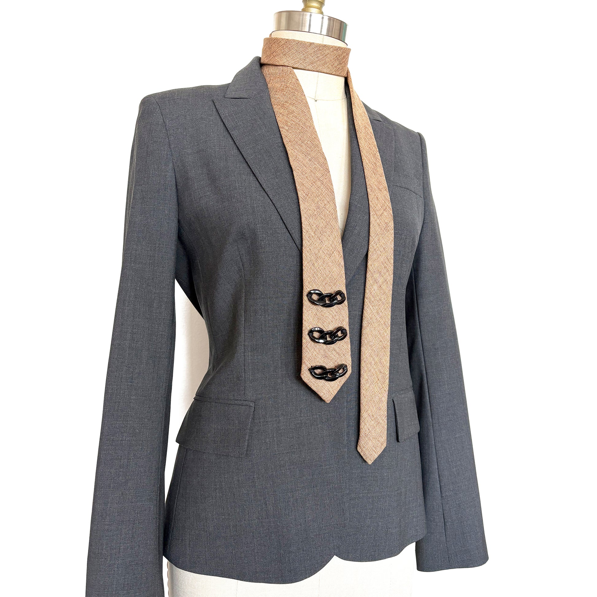 Camel tan necktie embellished with black decorative trim shown on mannequin with grey blazer