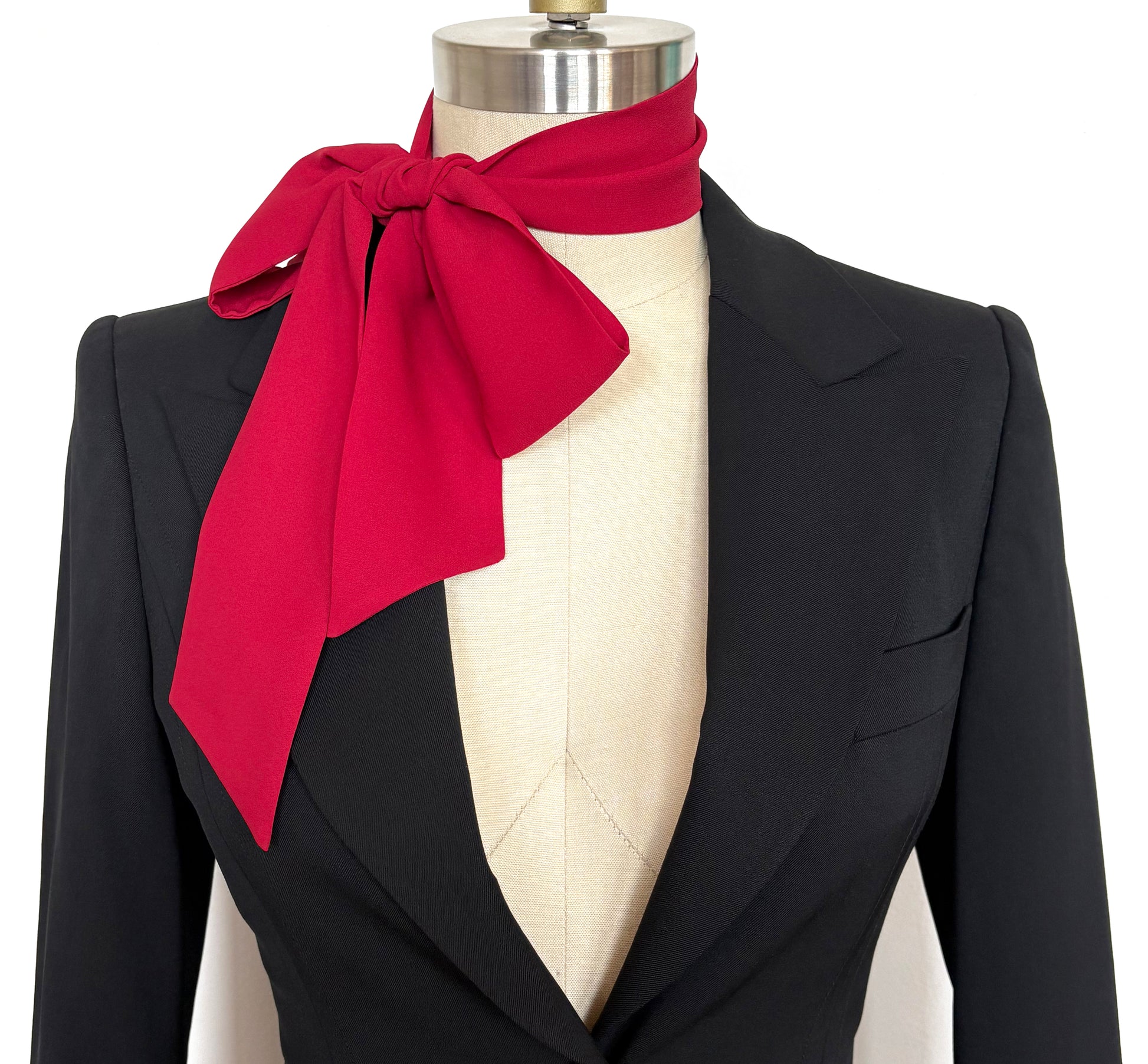 Black blazer with a red bow scarf on a mannequin against a white background