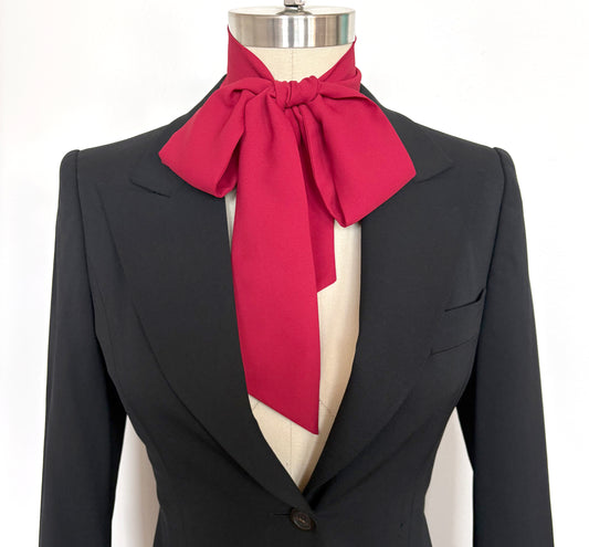 Black suit jacket with a red scarf tied around the neck on a mannequin against a white background