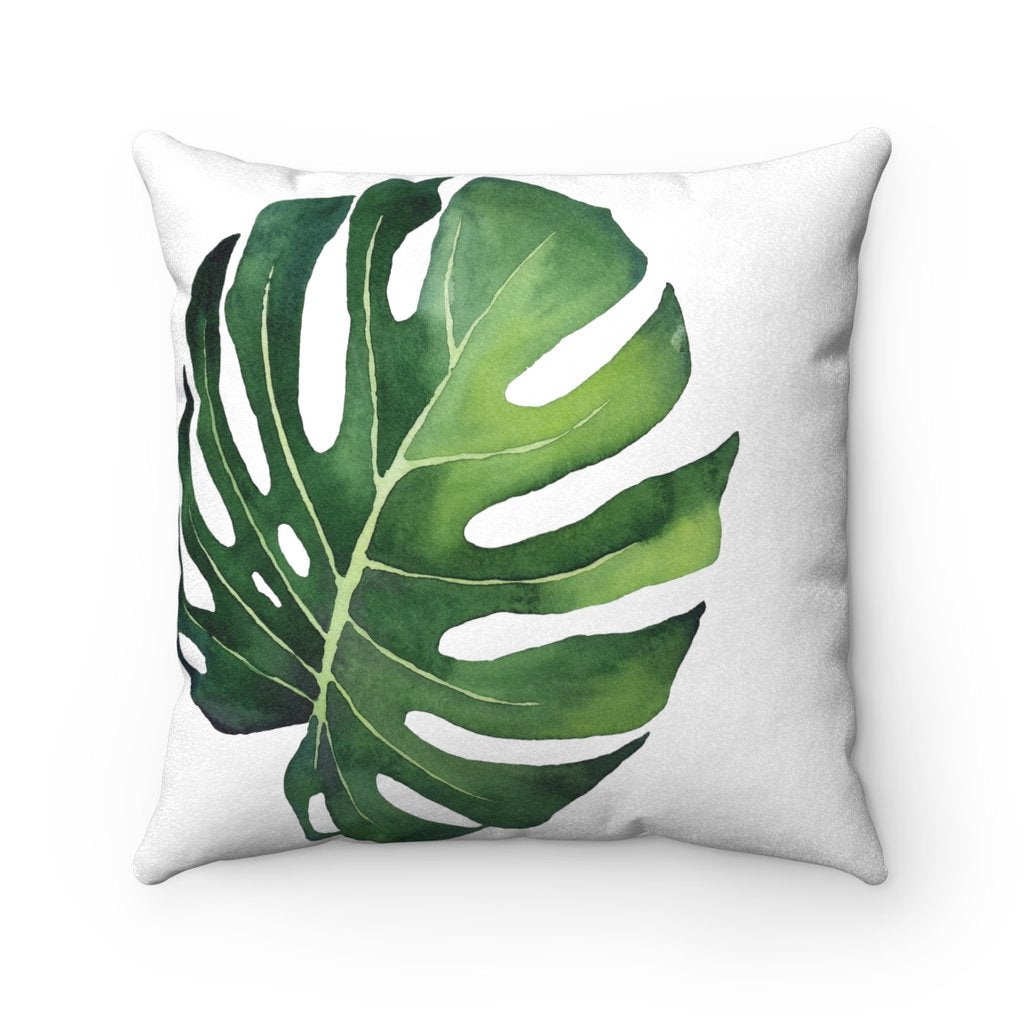 Pillow with a green tropical monstera leaf on a white background.