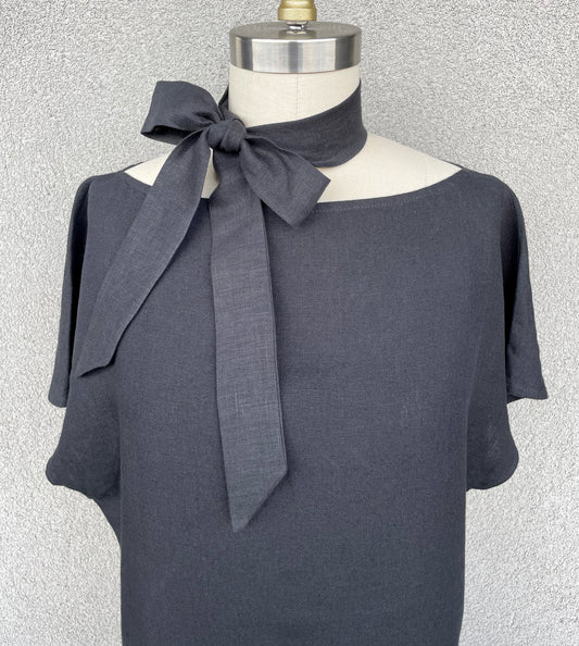 Black skinny linen scarf tied in bow worn on neck of mannequin with black blouse
