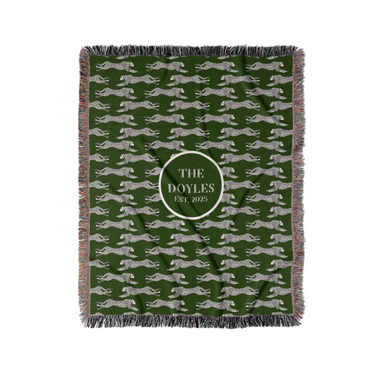 Black and cream cheetahs are woven into a dark green woven blanket or throw. Personalize with any custom text in center.