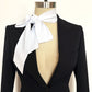 Black blazer with an oversized white bow tie on a mannequin against a white background