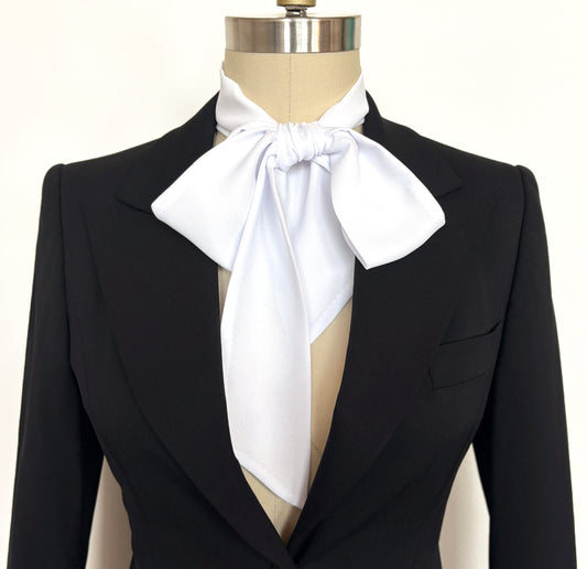 Black suit jacket with a blousy white bow tie on a mannequin against a white background