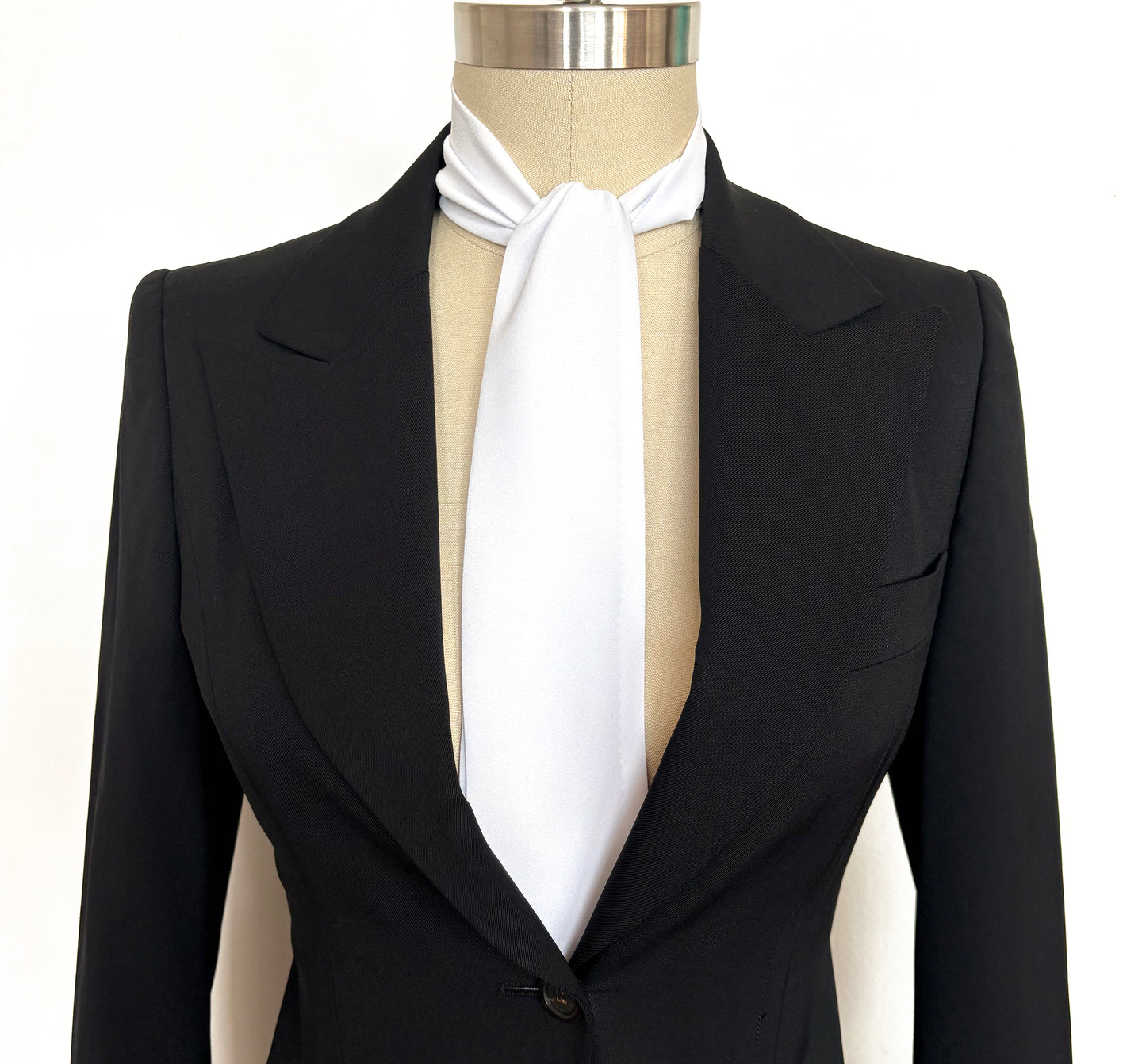 Black tuxedo with a white cravat on a mannequin against a white background