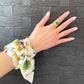 Thin floral scarf wrapped around wrist, worn as a bracelet.