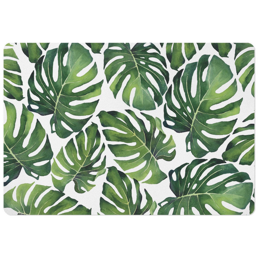 Tropical pet food mat with green monstera leaves.