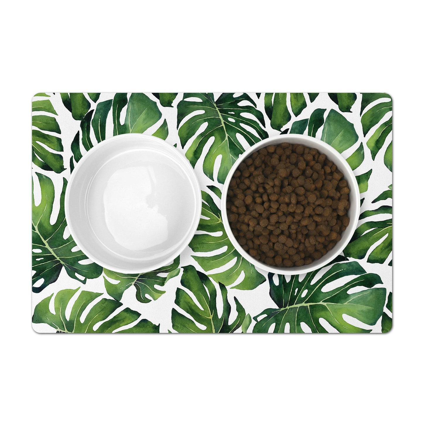Pet bowls mat under pet food bowls with green monstera leaves on white.