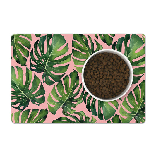 Pink Pet food mat with green monstera palm leaves under pet bowl.