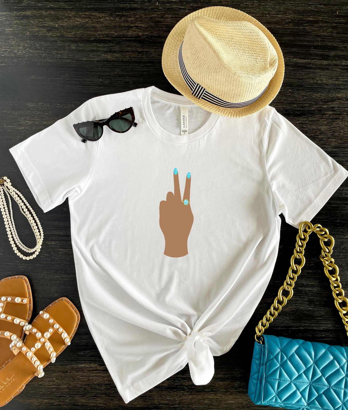 Peace Sign print t-shirt for women. Classic crewneck short sleeve tee features a hand wearing a glamorous aqua ring and a fabulous light blue manicure showing the peace sign. Fantastic gift for her.